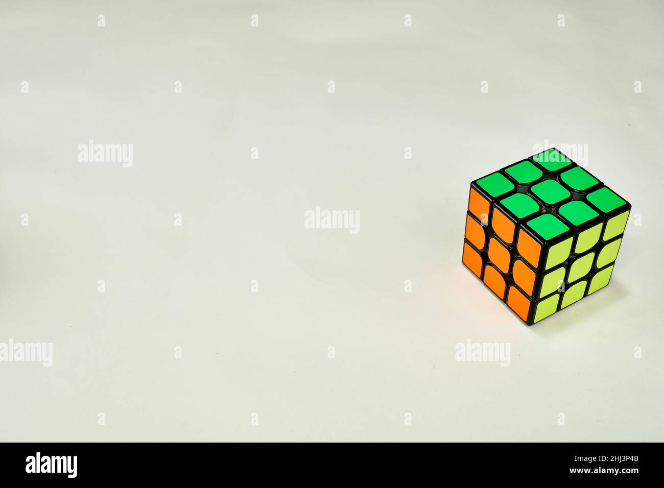 résolu le cube de rubik en jaune vert et orange sur fond blanc avec l'espace de copie 2 Banque D'Images