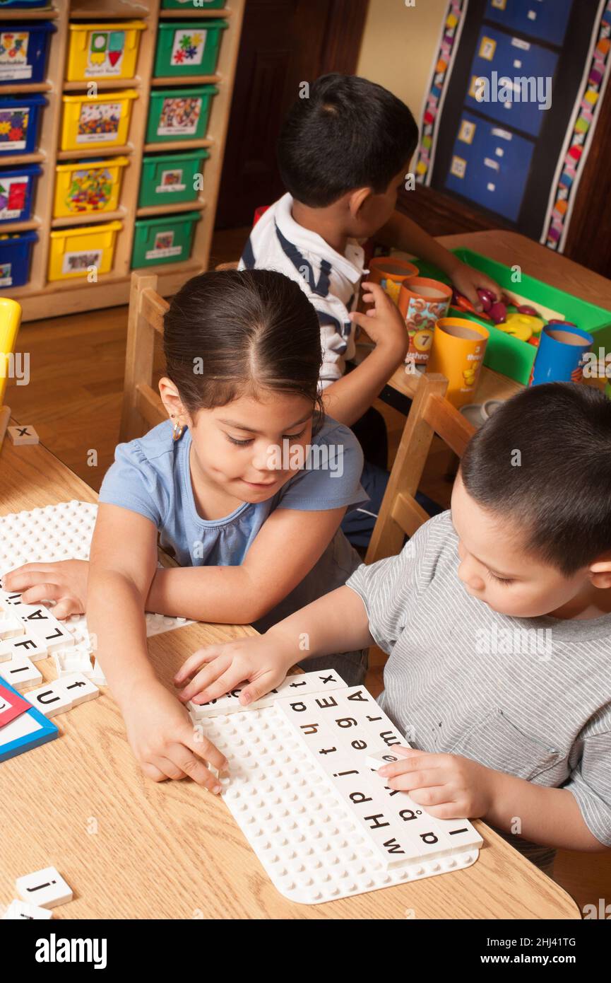 Éducation préscolaire 4-5 ans jeune fille et garçon jouant un jeu éducatif avec des lettres de l'alphabet Banque D'Images