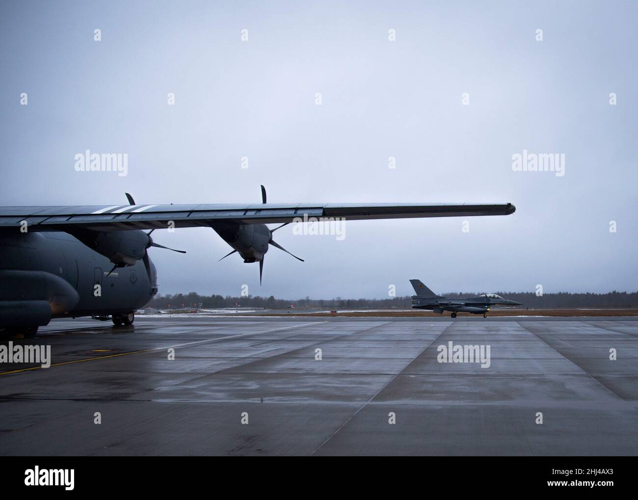 Un taxi F-16 belge devant un C-130J Super Hercules, affecté à l'aile du pont aérien 86th depuis la base aérienne de Ramstein, en Allemagne, à la base aérienne d'Ämari, en Estonie le 24 janvier 2022.Les C-130J et F-16 apportent leur soutien à une mission de police aérienne renforcée de l'OTAN.Le renforcement des services de police aérienne démontre la solidarité, la détermination collective de l’OTAN et sa capacité à adapter et à étendre ses missions défensives et sa posture de dissuasion en réponse à l’évolution de la situation sécuritaire de l’alliance.(É.-U.Photo de la Force aérienne par le sergent d'état-major.Megan Beatty) Banque D'Images