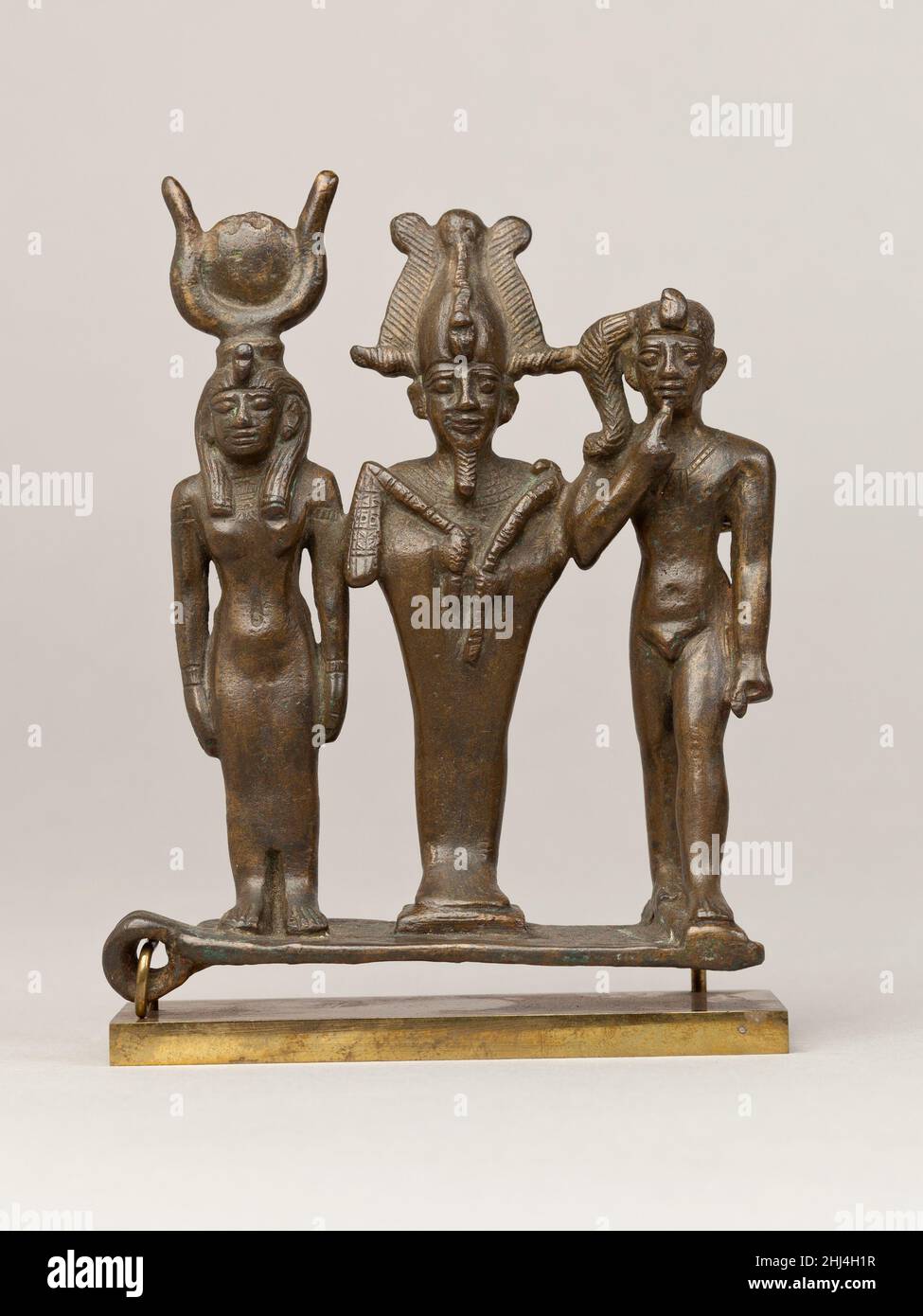 Triade d'Osiris, d'Isis et d'Horus 664–30 C.-B. période tardive–période Ptoléméenne les dieux très populaires Osiris, Isis et Harpokrates sont ici représentés comme triade debout d'affilée sur une seule base.Plusieurs boucles étudient le groupe - une projetant du côté de la base à angles droits, et d'autres derrière Harpokrates et Osiris: S'ils sont destinés à permettre la fixation dans des contextes multiples, ou plutôt un ajout plus symbolique, est une question.Triade d'Osiris, d'Isis et d'Horus.664–30 C.-B.Métal Cuprous.Période tardive–période de Ptolemaic.De l'Égypte Banque D'Images