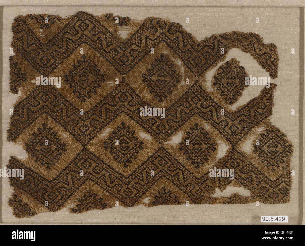 Fragment textile 14th siècle ce fragment se compose d'un tissage de lin non tissé avec brocart en soie noire.Le motif est formé de bandes zigzag qui créent des diamants autour d'elles, dans lesquelles une forme en losange est insérée.Outre les contours noirs épais et distinctifs, la soie noire est également utilisée pour créer un sol en pointillés dans les bandes et la forme en forme de losange.La régularité de la répétition suggère que le tissu original peut avoir été une plus grande pièce, peut-être un boulon de textile.Fragment textile 443915 Banque D'Images