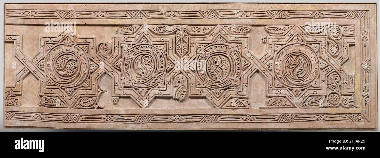 Panneau de Dado 10th siècle en 1935, une équipe d'archéologues du Metropolitan Museum a commencé à fouiller un monticule connu sous le nom de Sabz Pushan (le couvert vert), situé près de la ville de Nishapur.L'excavation a découvert une partie d'un quartier résidentiel du dixième siècle avec plusieurs unités richement décorées de stuc sculpté et peint.Ce panneau a été assemblé à partir de fragments de stuc sculpté trouvés sur le plancher de l'une de ces unités, après s'être effrité d'un mur voisin où ils ont formé à l'origine un long dado.La décoration principale du panneau se compose d'une bande d'étoiles à huit points, chacune remplie d'un peu Banque D'Images