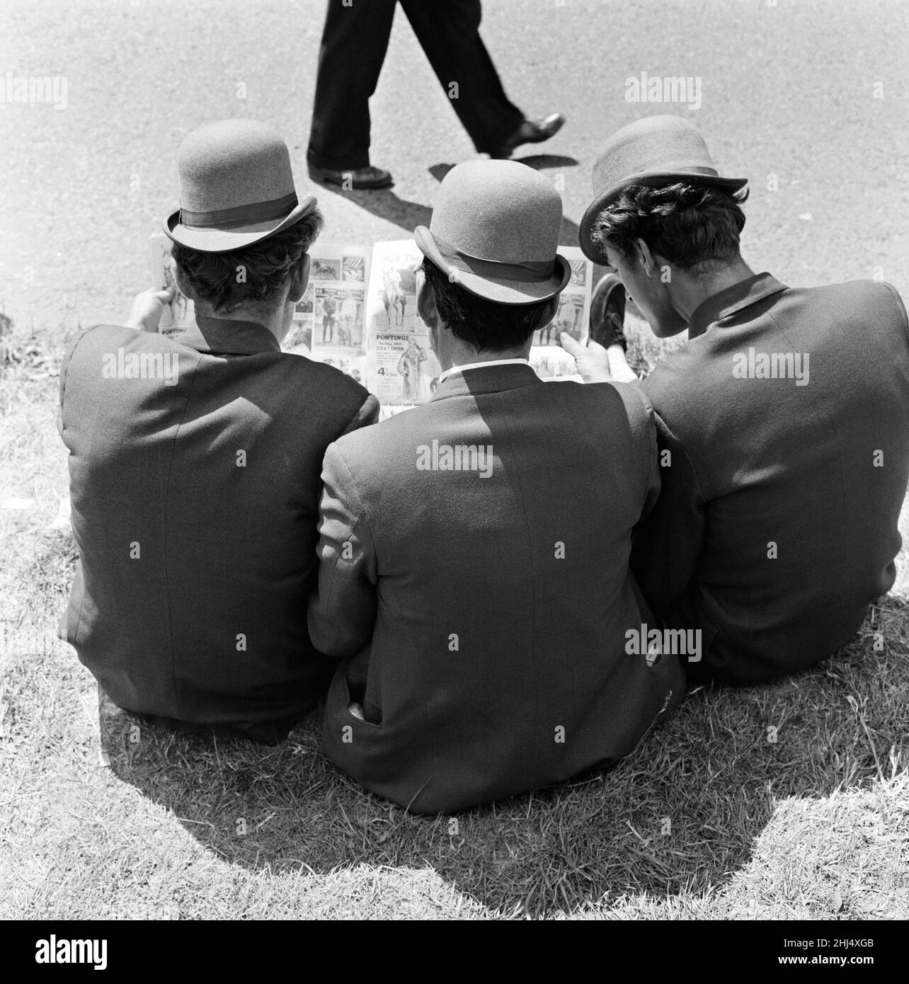 Derby Day à Epsom.Sur la photo, trois lads de Newmarket assis sur la forme d'étude de l'herbe.Tous portent des chapeaux qu'ils décrivent comme des « hariteuses dures », ils sont semblables aux baleines mais ont une visière courbée.3rd juin 1959. Banque D'Images