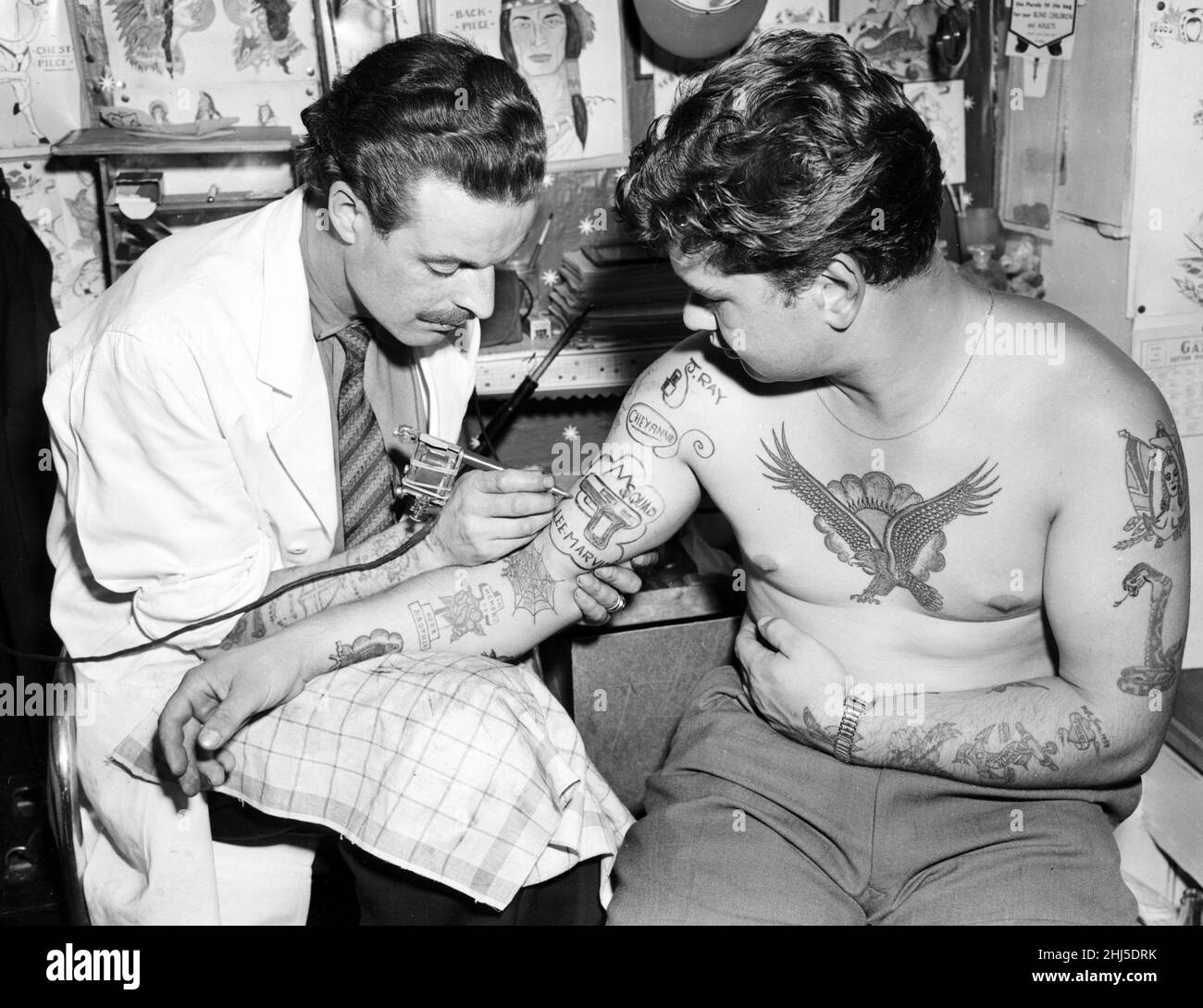 Tatoueur de Blackpool Harry lever tatouages un client.La nouvelle folie est pour les héros de la télévision - le lawman Cheyenne, Dan Mathews de la patrouille routière et Frank Ballinger de M Squad ont tous été populaires.29th juillet 1957. Banque D'Images