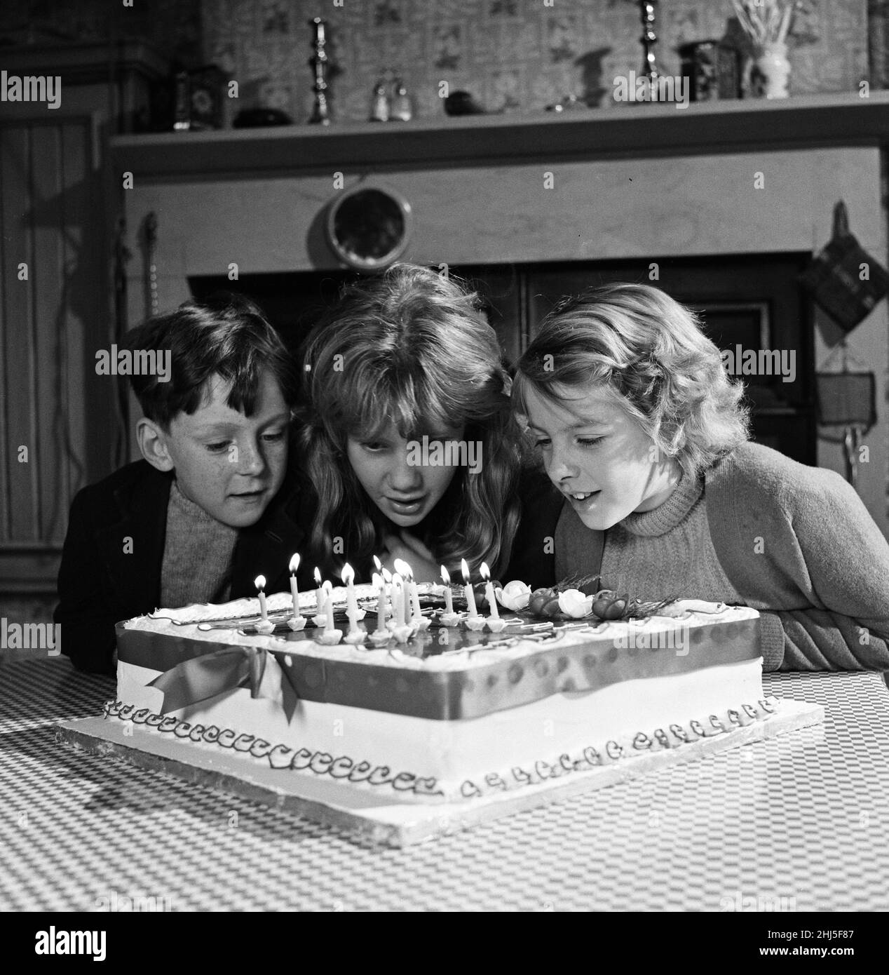 La star de cinéma Hayley Mills célèbre son anniversaire de 15th aux Pinewood Studios où elle filme « siffle Down the Wind ».Le studio a présenté à Hayley un gâteau qu'elle a partagé avec le reste de la troupe.Elle est photographiée en soufflant les bougies avec Alan Barnes (7 ans, à gauche) et Diane Holgate (10 ans).18th avril 1961. Banque D'Images