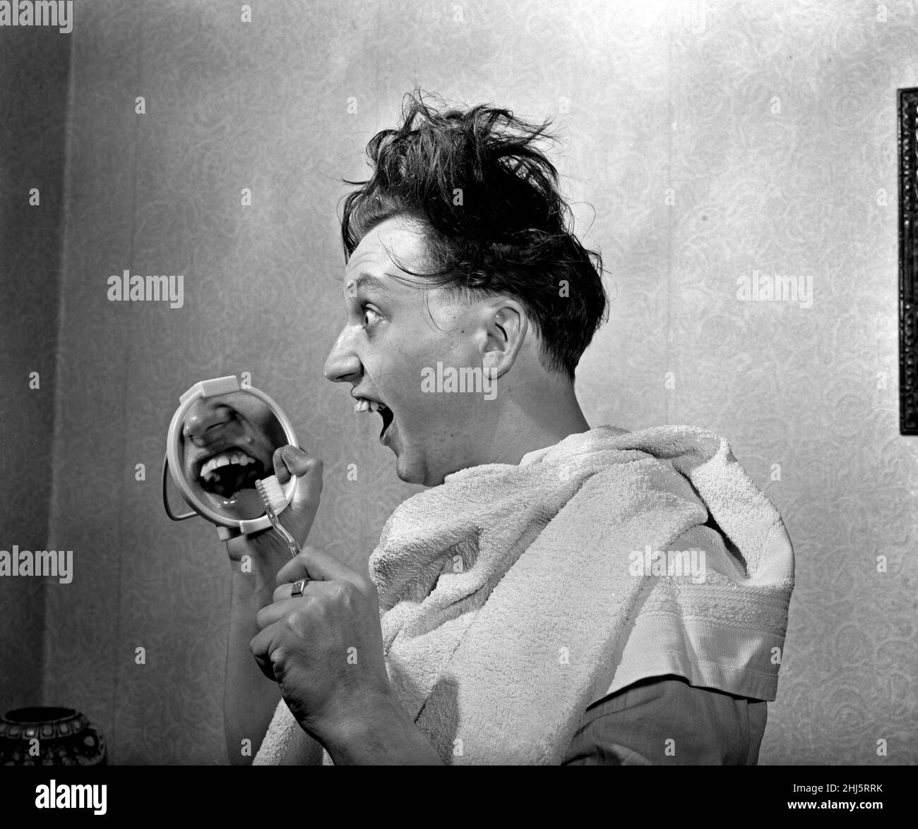 Chaque matin, le comédien Ken Dodd regarde à £10 000 valeur de 'sparaklers' - ses dents.Ken a assuré ses dents proéminentes et saillantes pour £10 000 avec un courtier d'assurance Birmingham.Cela lui coûtera £25 par an et il doit nettoyer ses dents trois fois par jour avec une marque acceptée de dentifrice et il ne doit pas manger de rock.Ken est photographié pour nettoyer ses spaces.4th avril 1957. Banque D'Images