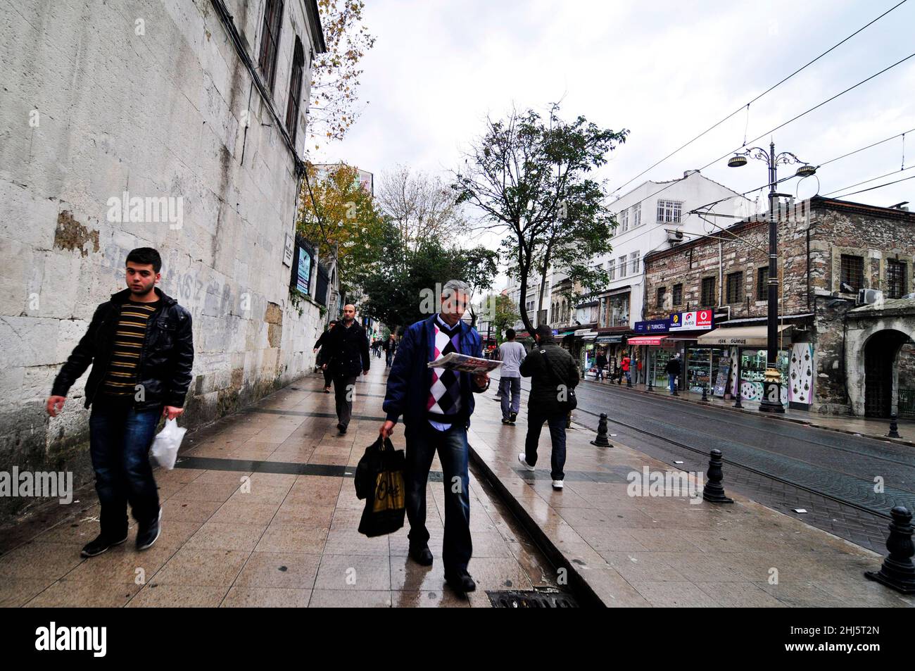 Un turc lisant le journal du matin tout en marchant jusqu'à son bureau de Fatih, Istanbul, Turquie. Banque D'Images