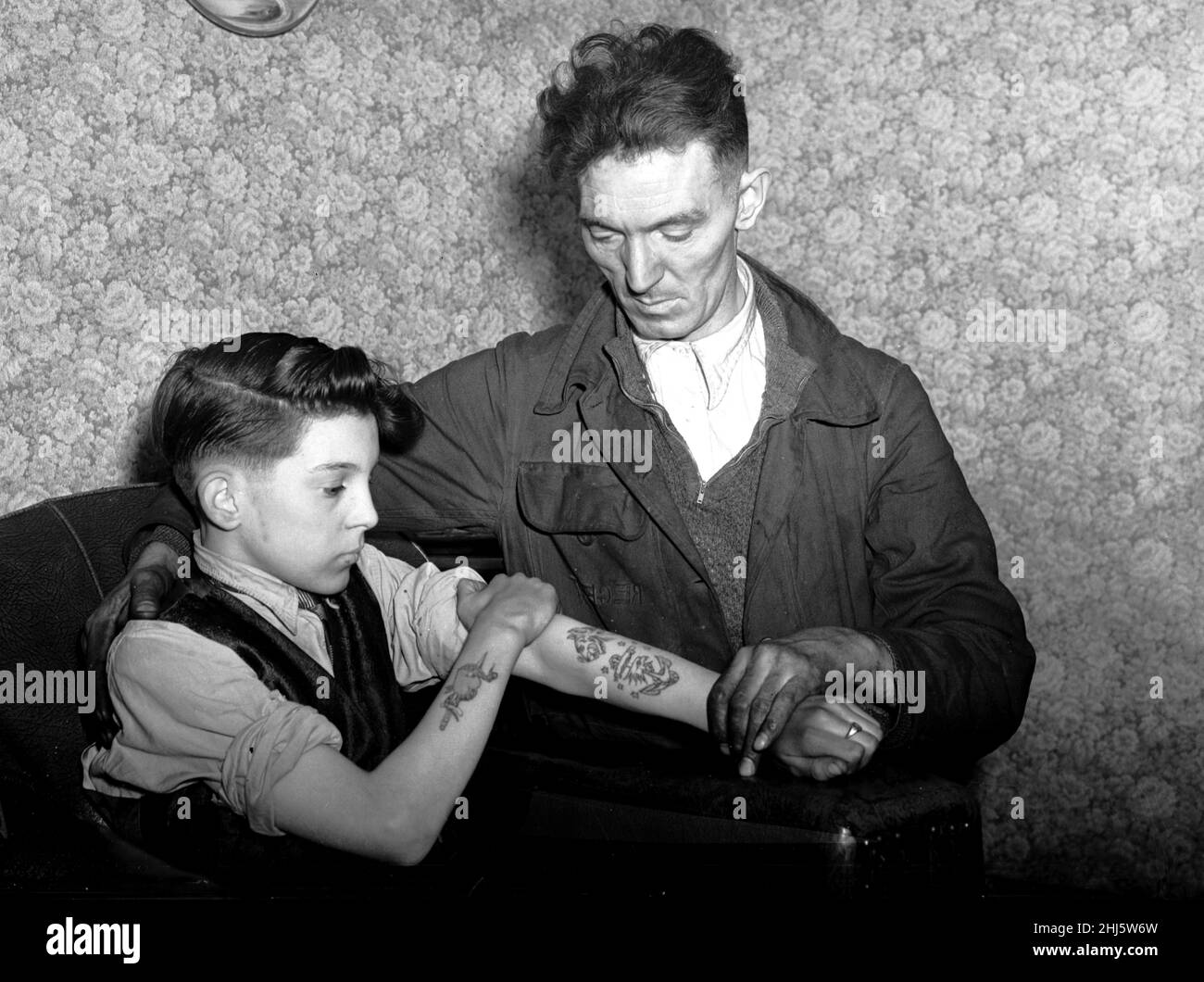 Arthur Waterworth, 14 ans, de Droylsden, présente ses avant-bras tatoués à son père.13th janvier 1956. Banque D'Images