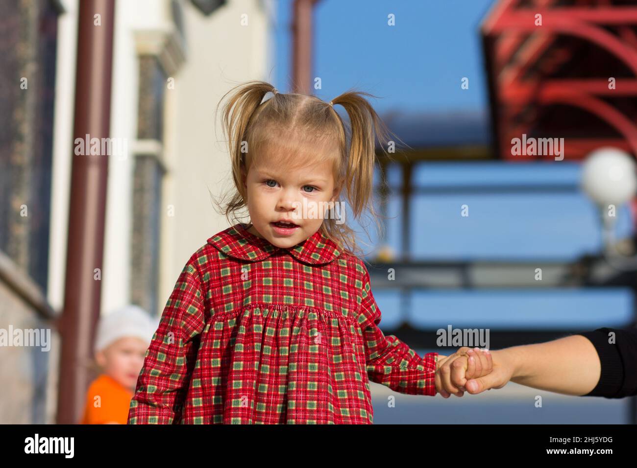 Portrait de l'enfant caucasien heureux de deux ans tenant les mains de la mère en été Banque D'Images
