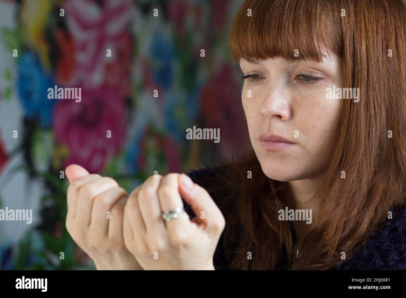 Portrait d'une femme d'âge moyen regardant ses ongles désaimés Banque D'Images