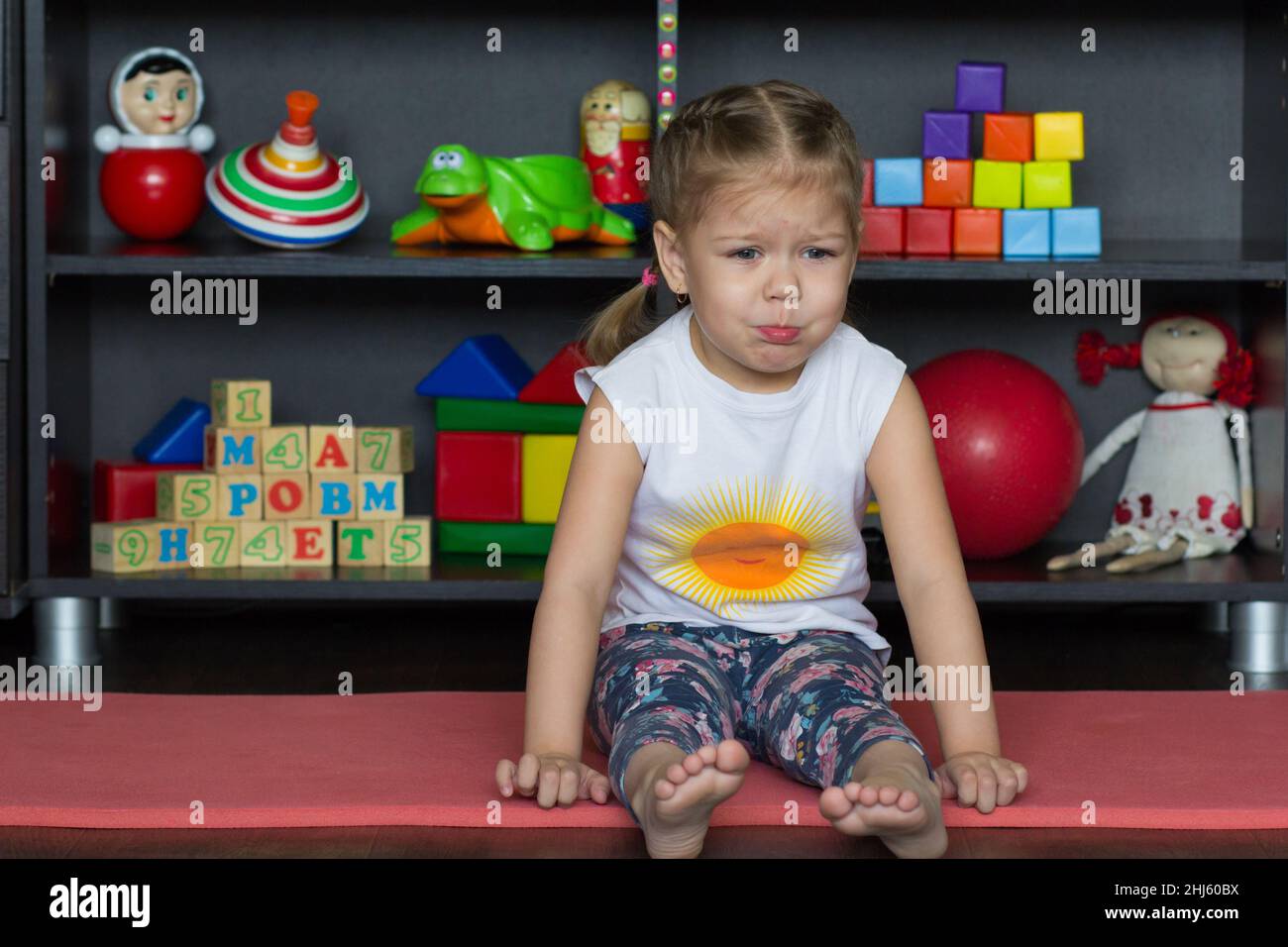 Triste et allant pleurer petite fille assis sur le sol à l'intérieur Banque D'Images