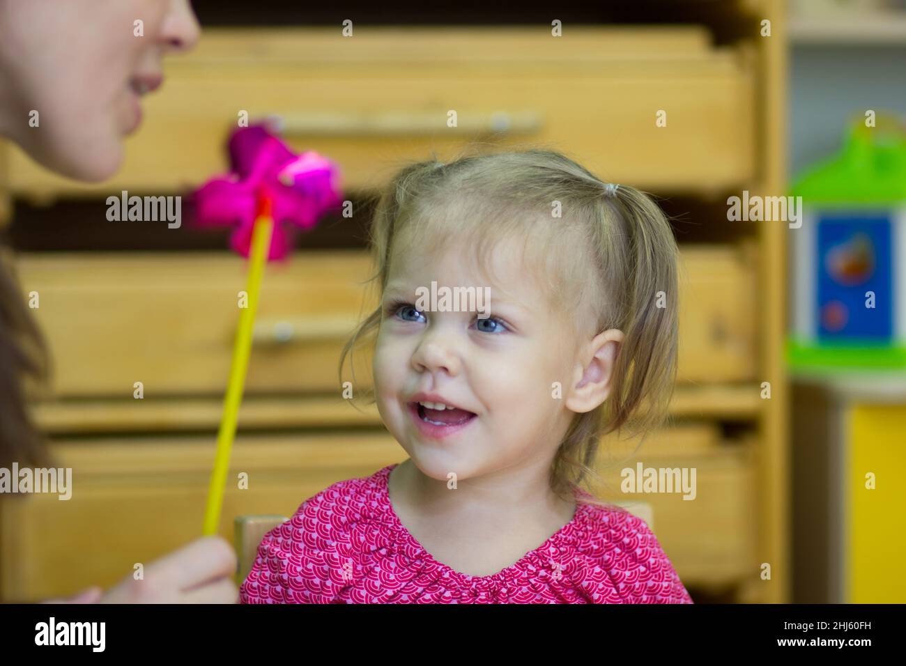 Professeur expliquant à un enfant caucasien de deux ans comment souffler sur le jouet intérieur Banque D'Images
