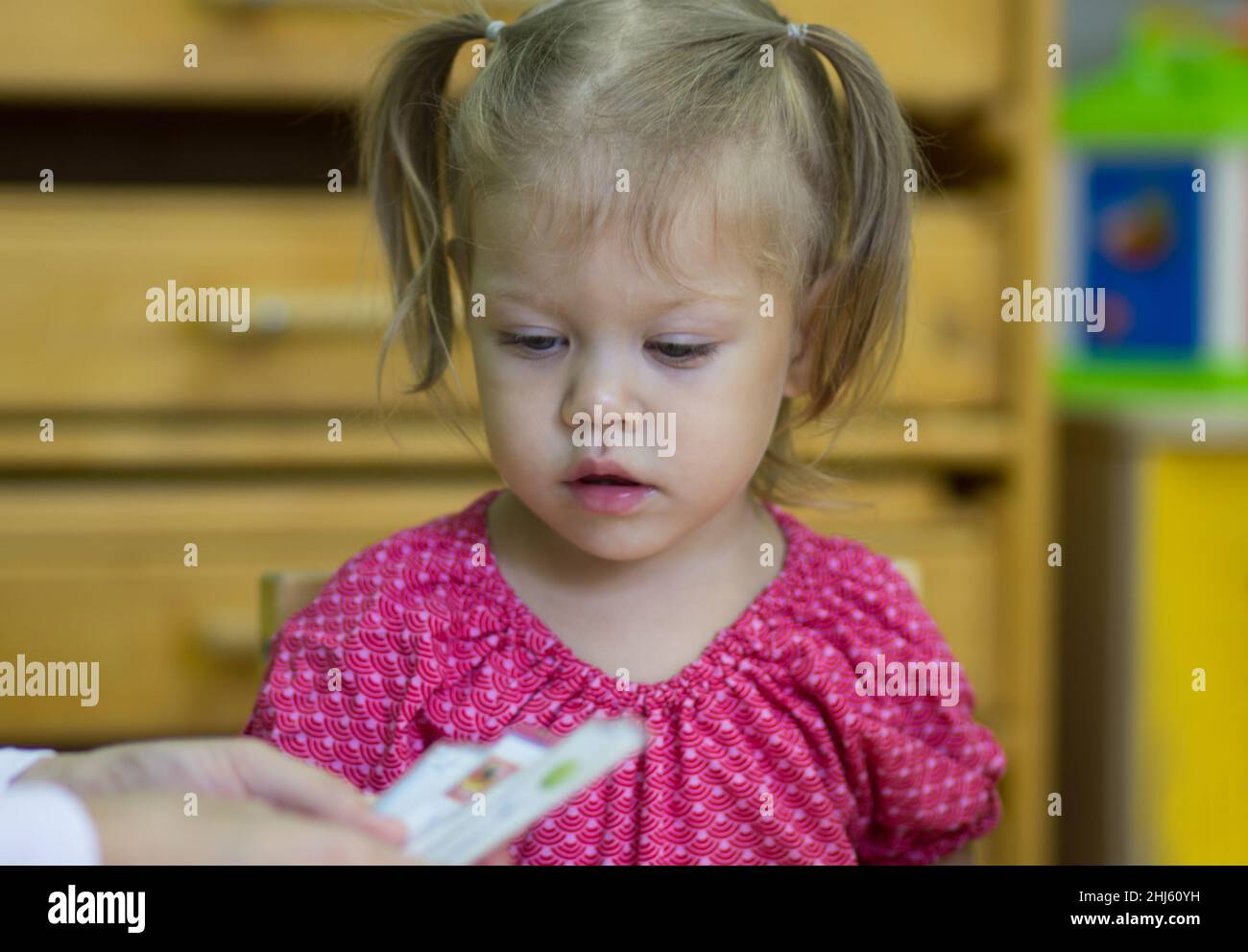Portrait d'un enfant de race blanche de deux ans regardant des cartes en classe exercice à l'intérieur Banque D'Images