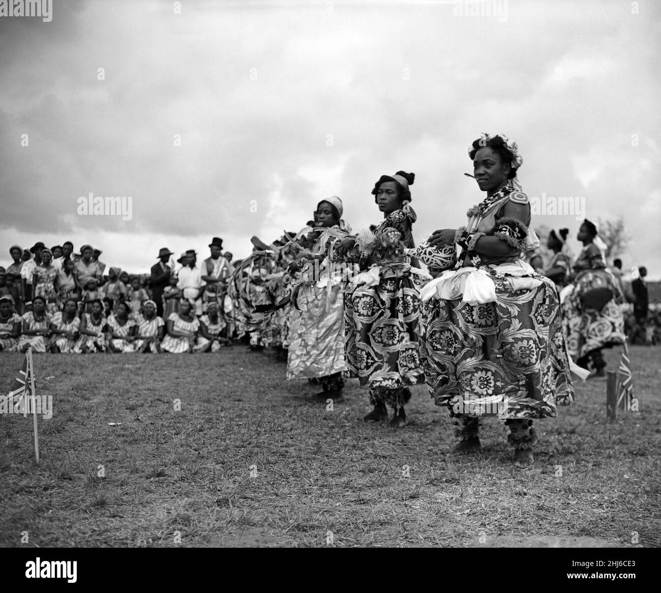 Une danseuse nigériane de la tribu Efik s'arrête à la fin d'une danse traditionnelle pour la reine et le duc d'Édimbourg lors de leur tour royal.Le Ntimi est la danse cérémoniale suprême des femmes de Calabar et n'est exécuté que lors de grandes occasions publiques.Deux éléments importants du costume sont la plume rouge tenue entre les lèvres pour assurer le silence et un gourde qui est manipulé avec art pour transmettre des messages de loyauté.Calabar, Nigéria.8th février 1956. Banque D'Images