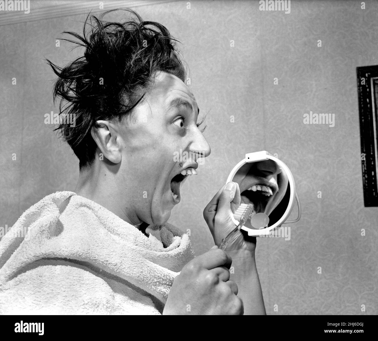 Chaque matin, le comédien Ken Dodd regarde à £10 000 valeur de 'sparaklers' - ses dents.Ken a assuré ses dents proéminentes et saillantes pour £10 000 avec un courtier d'assurance Birmingham.Cela lui coûtera £25 par an et il doit nettoyer ses dents trois fois par jour avec une marque acceptée de dentifrice et il ne doit pas manger de rock.Ken est photographié pour nettoyer ses spaces.4th avril 1957. Banque D'Images