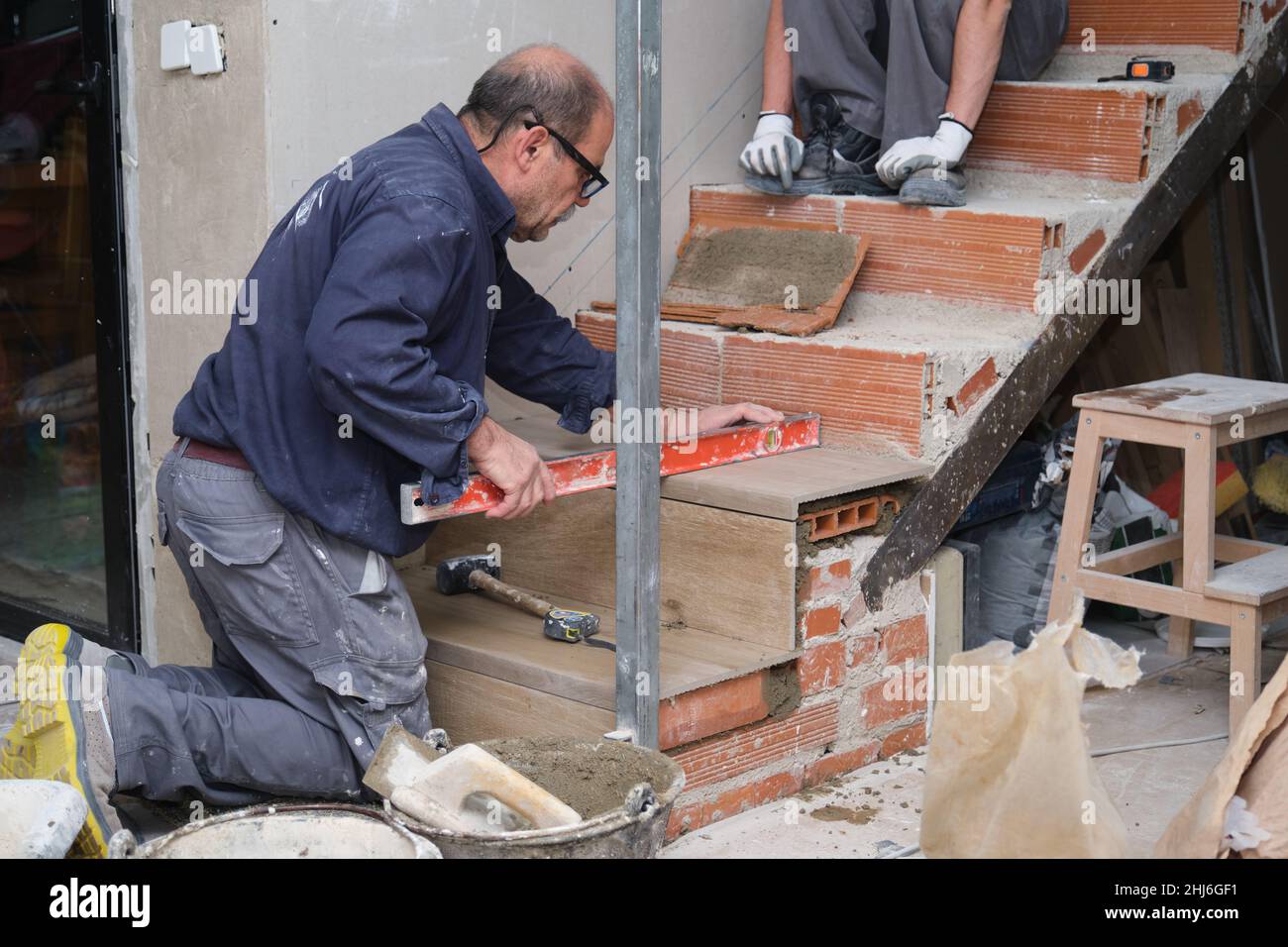 Couche de briques senior utilisant un niveau à bulle pour vérifier que le marchepied est horizontal. Banque D'Images