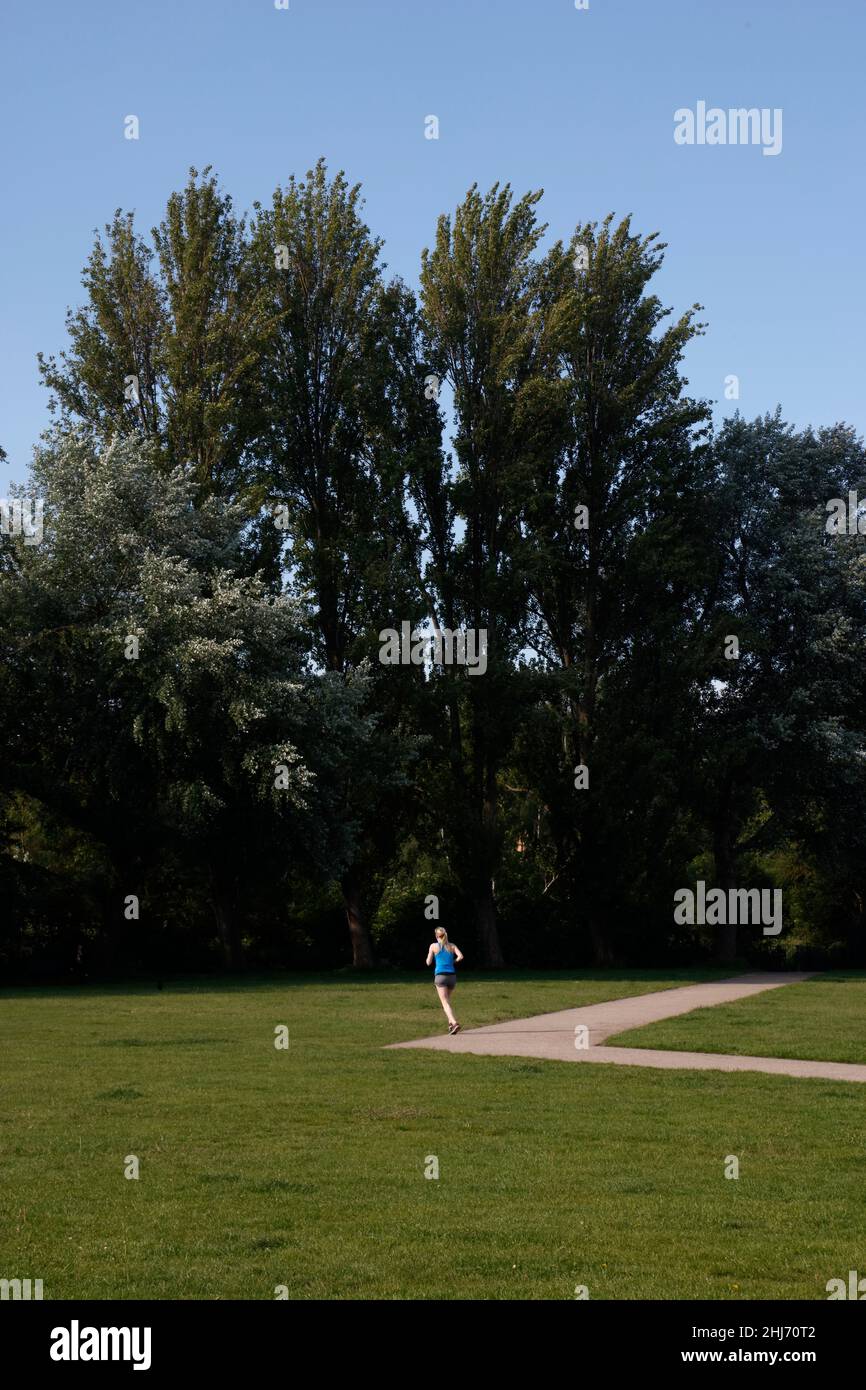 Jogging traversant le parc King George, Southfields, Londres, Royaume-Uni Banque D'Images Jogging traversant le parc King George, Southfields, Londres, Royaume-Uni Banque D'Images