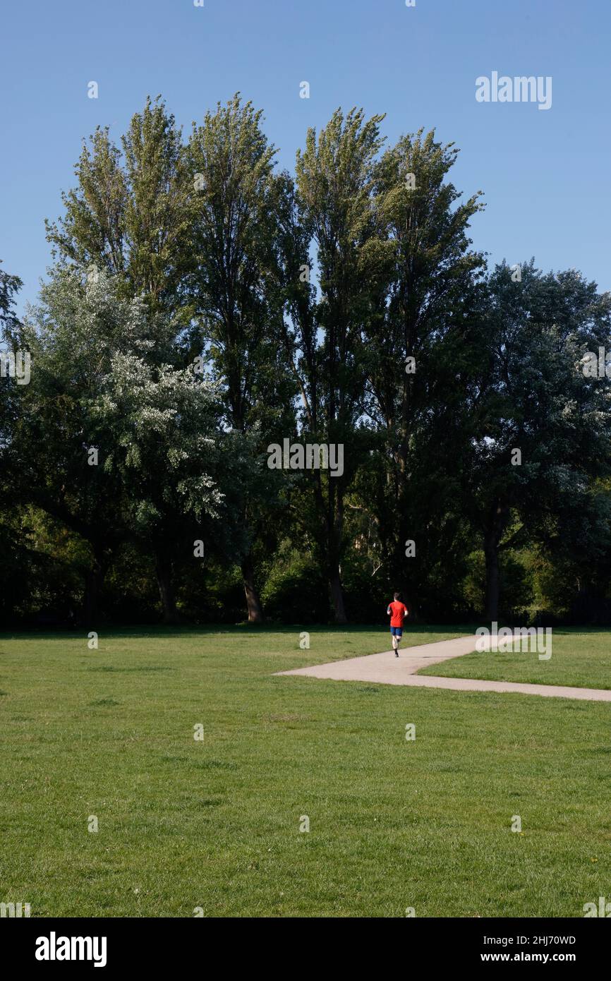 Jogging traversant le parc King George, Southfields, Londres, Royaume-Uni Banque D'Images Jogging traversant le parc King George, Southfields, Londres, Royaume-Uni Banque D'Images