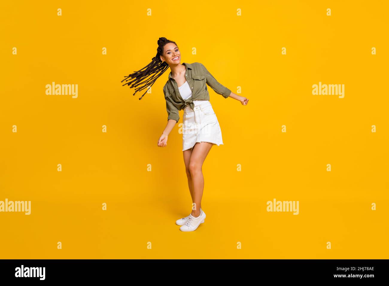 Portrait photo pleine longueur de mignonne fille balançoire cheveux isolés sur fond jaune vif de couleur Banque D'Images