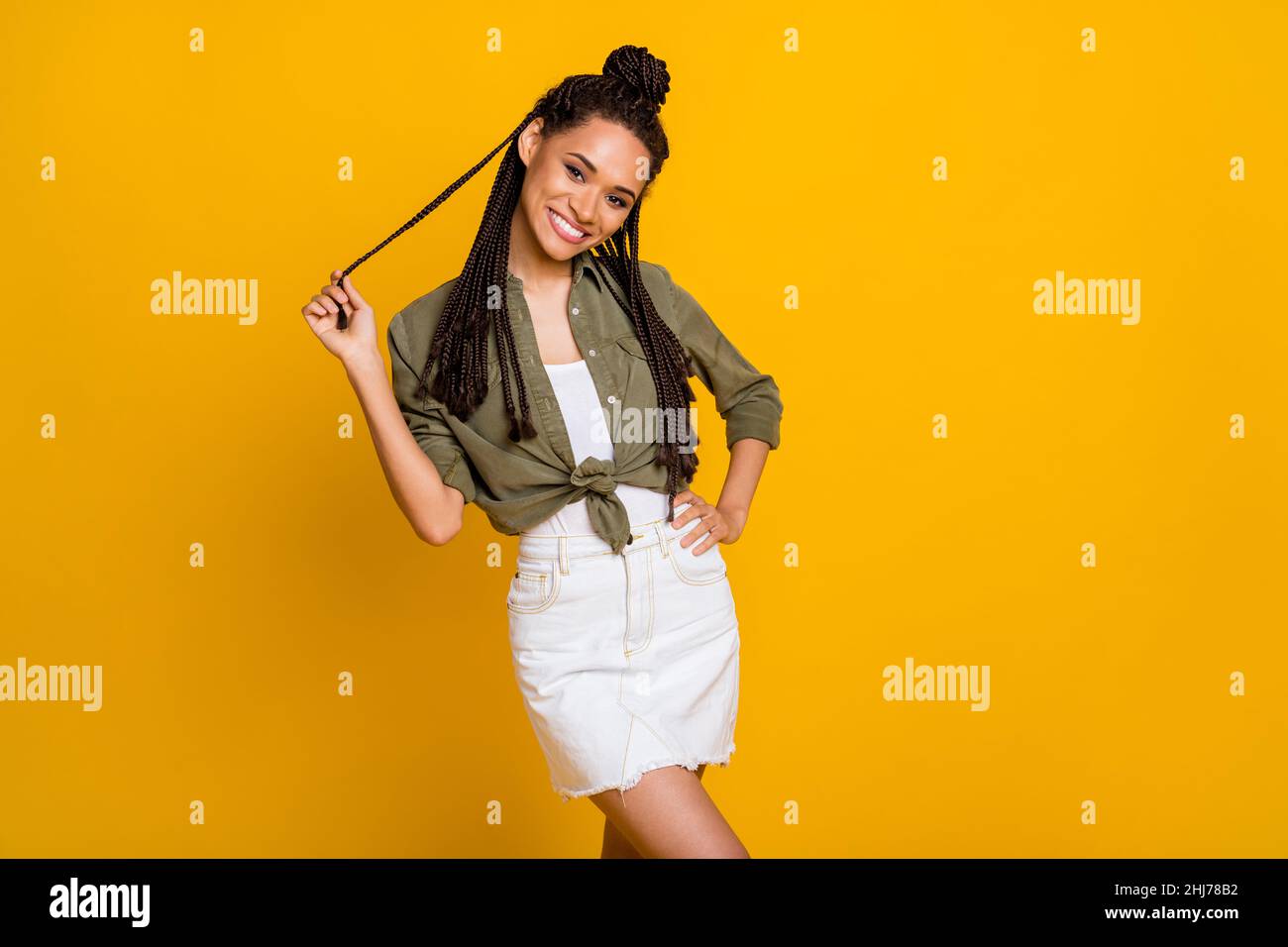 Photo portrait d'une femme jouant avec des cheveux isolés sur fond jaune vif Banque D'Images