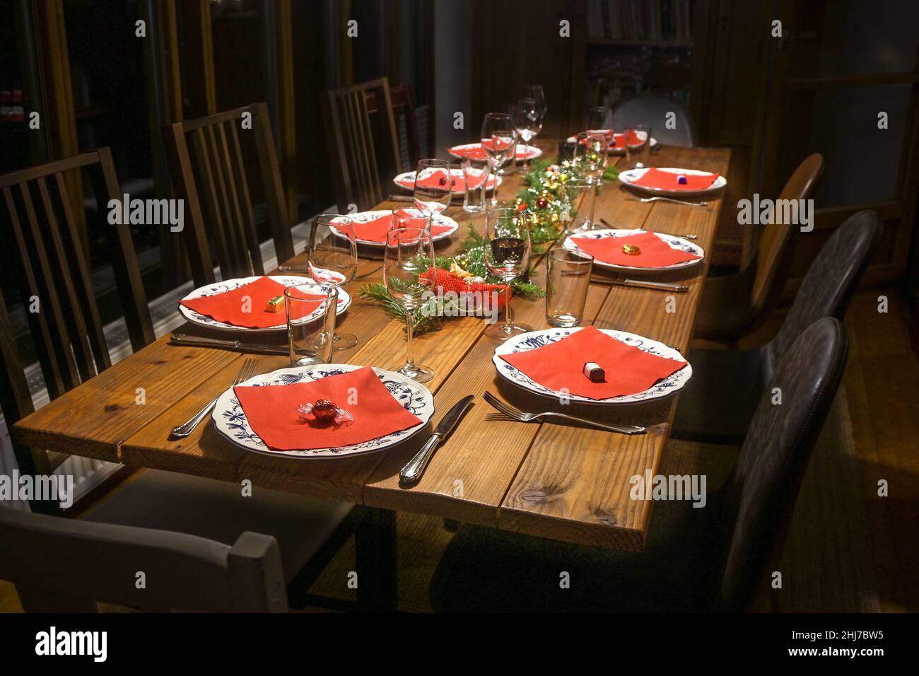 Table familiale en bois rustique avec assiettes, serviettes rouges et verres pour un dîner festif entre amis, sélection, champ étroit Banque D'Images