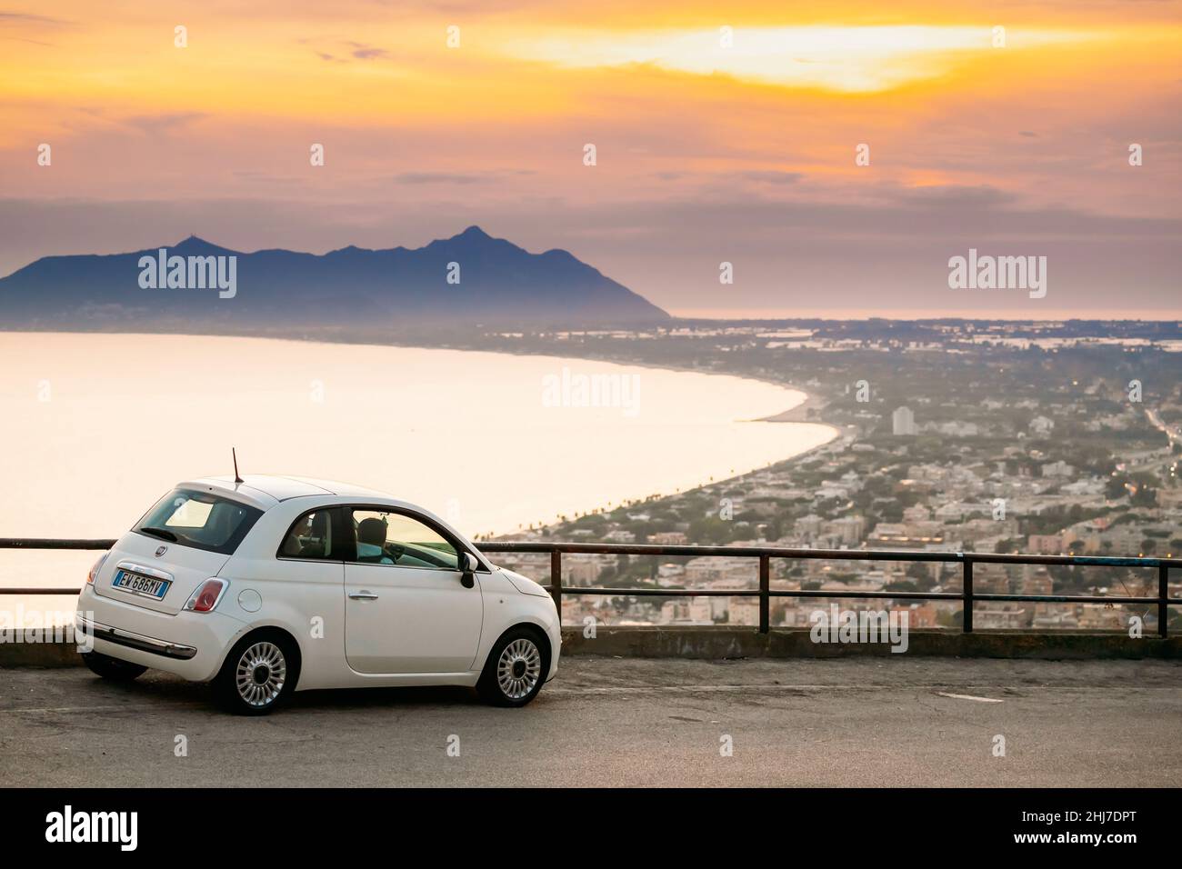 Terracina, Italie.Couleur blanche Fiat 500 Facelift 2016 voiture garée sur fond Circeo Promontory et la mer Tyrrhénienne au coucher du soleil ou au lever du soleil Banque D'Images