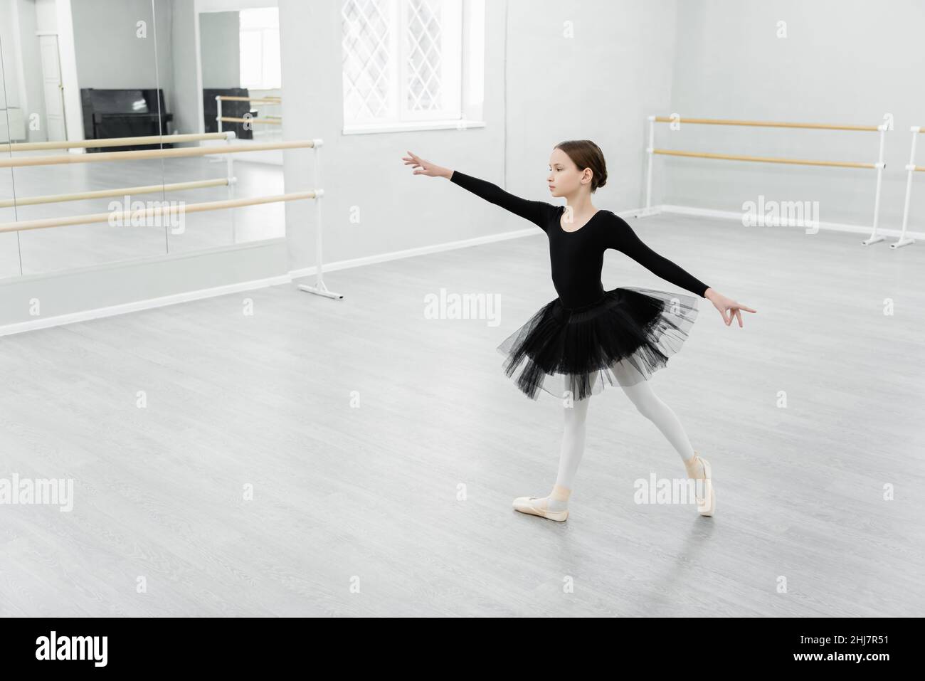 vue en longueur de fille en tutu noir dansant pendant la répétition dans le studio Banque D'Images