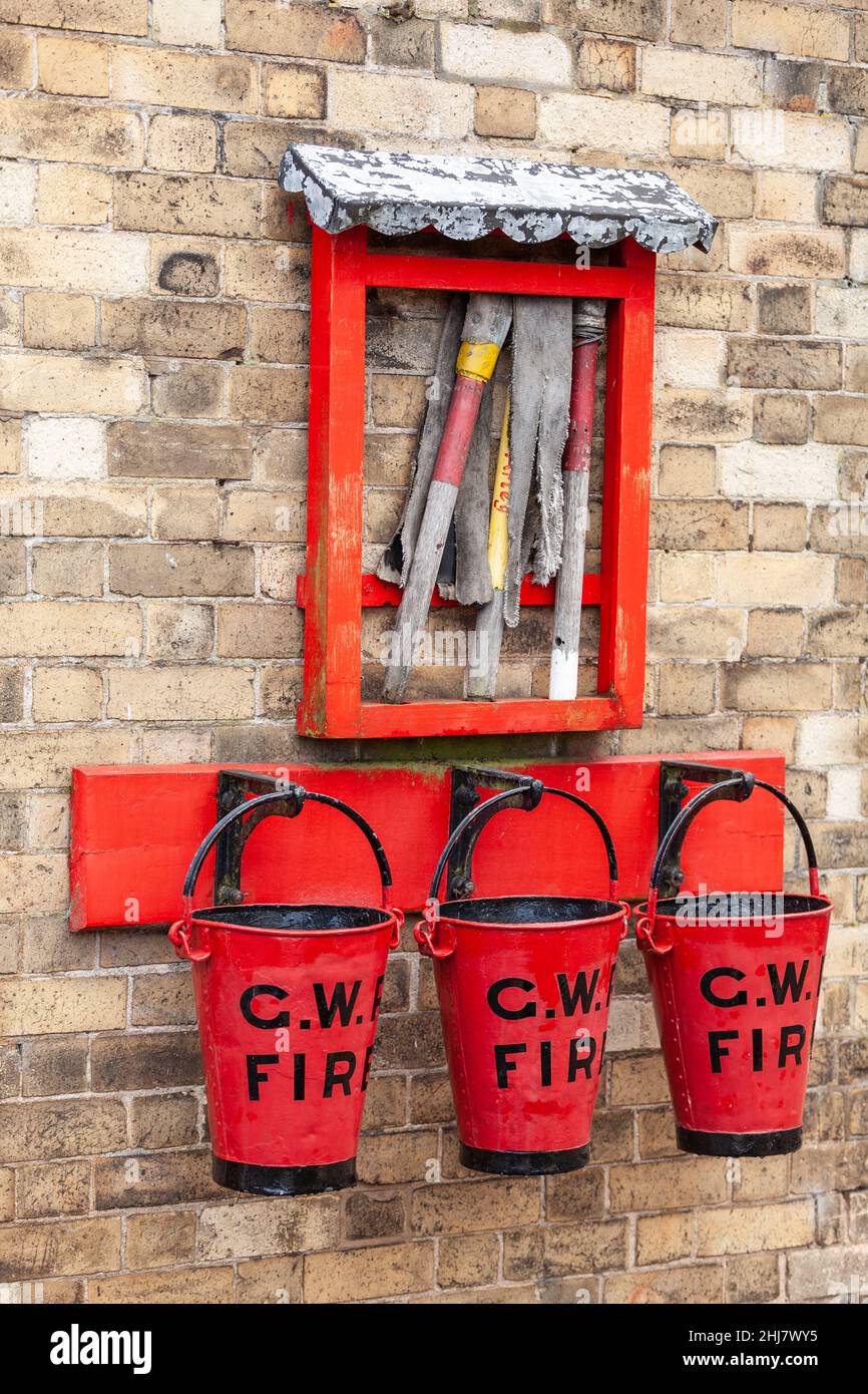 Seaux d'incendie GWR rouge vif et équipement de lutte contre les incendies sur le vieux mur de brique Banque D'Images
