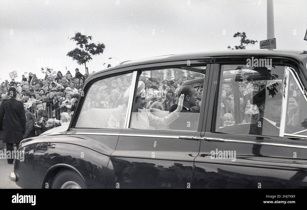 1977, des visages heureux historiques et des drapeaux de l'Union Jack alors que sa Majesté, la reine Elizabeth II et le prince Philip assis dans son véhicule officiel, une Rolls-Royce Phanton VI, font signe à la foule au bord de la route, Londres, Angleterre, Royaume-Uni pendant les célébrations de la Jubliee d'argent. Banque D'Images