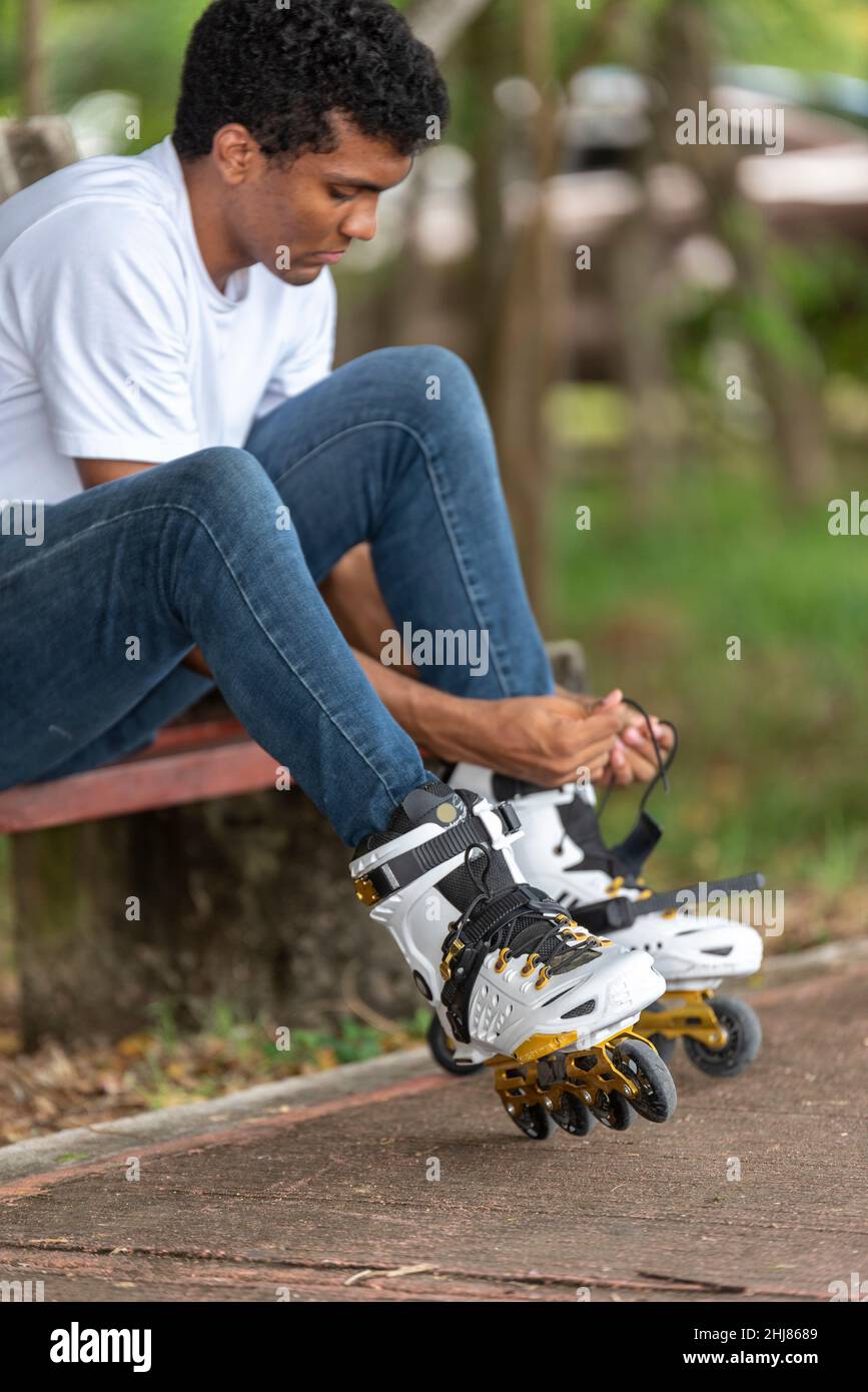 Jeune homme latino assis sur des patins en ligne Banque D'Images