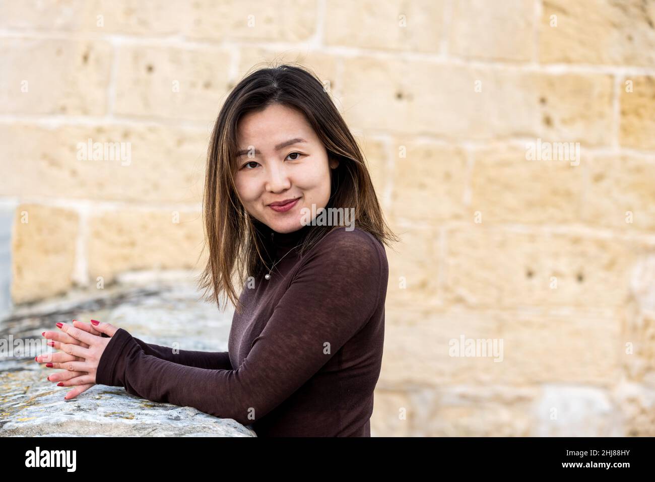 Portrait d'une fille américaine asiatique de 29 ans debout sur une forteresse, mains pliées Banque D'Images