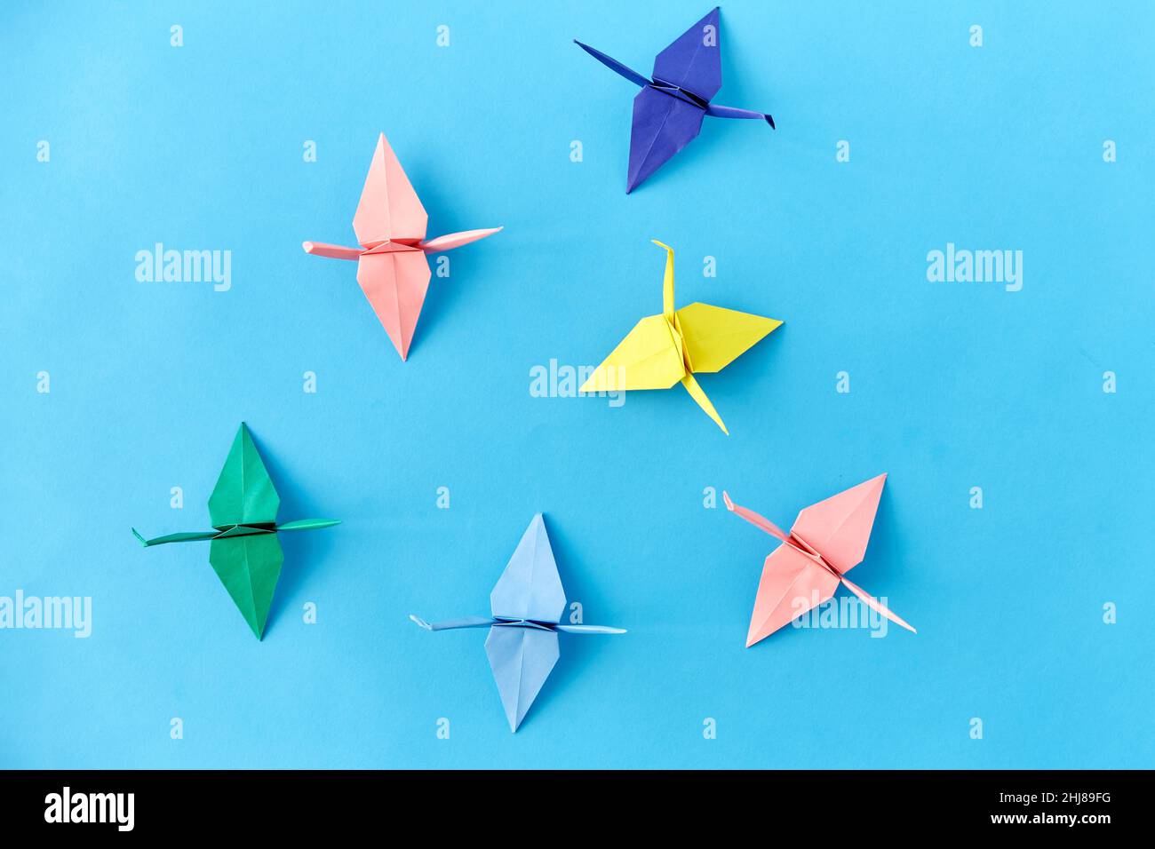 grues en papier origami sur fond bleu Banque D'Images
