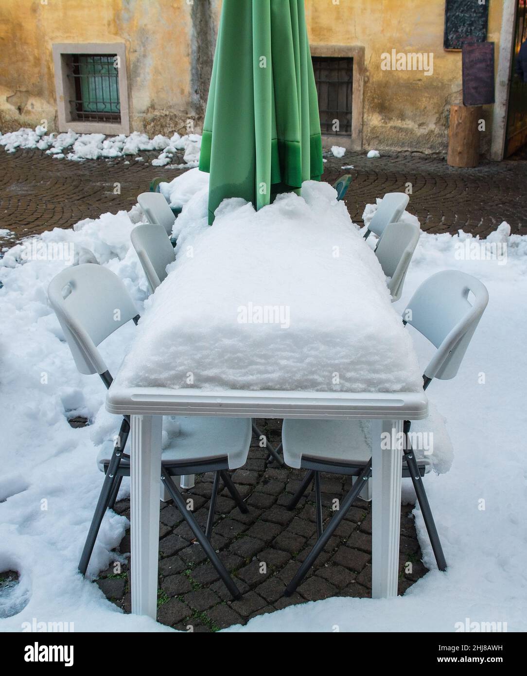 Une épaisse couche de neige recouvre une table et des chaises devant un restaurant dans le centre historique de la ville italienne du nord-est de Belluno, région de la Vénétie.Décembre Banque D'Images
