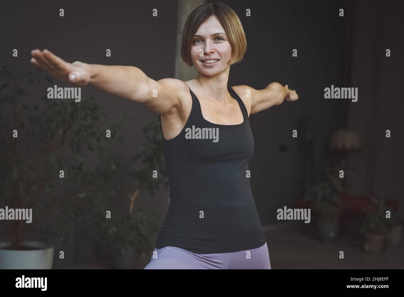 Jeune femme exécutant Viradrasana 2 ou guerrier pose 2 à la maison.Instructeur de yoga à faire des poses d'étirement à l'intérieur moderne de la maison.Concept de style de vie sain.Concept de méditation. Banque D'Images