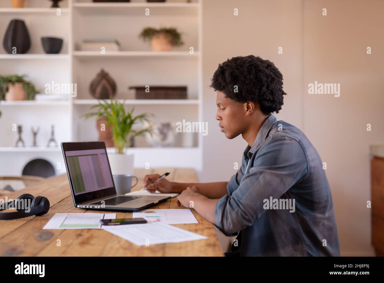 Vue latérale de jeunes hommes d'affaires afro-américains écrivant tout en utilisant un ordinateur portable à la table. Non modifié, affaires, technologie sans fil, lecture, concentration, Banque D'Images