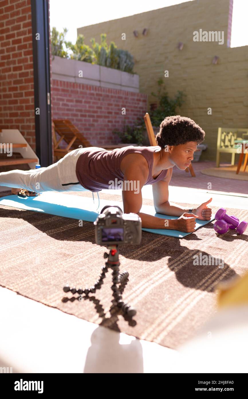Afro-américain jeune homme faisant des push-ups vlog à la maison. Non modifié, fitness, vlogging, stretching, appareil photo,haltères, influenceur et mode de vie actif c Banque D'Images