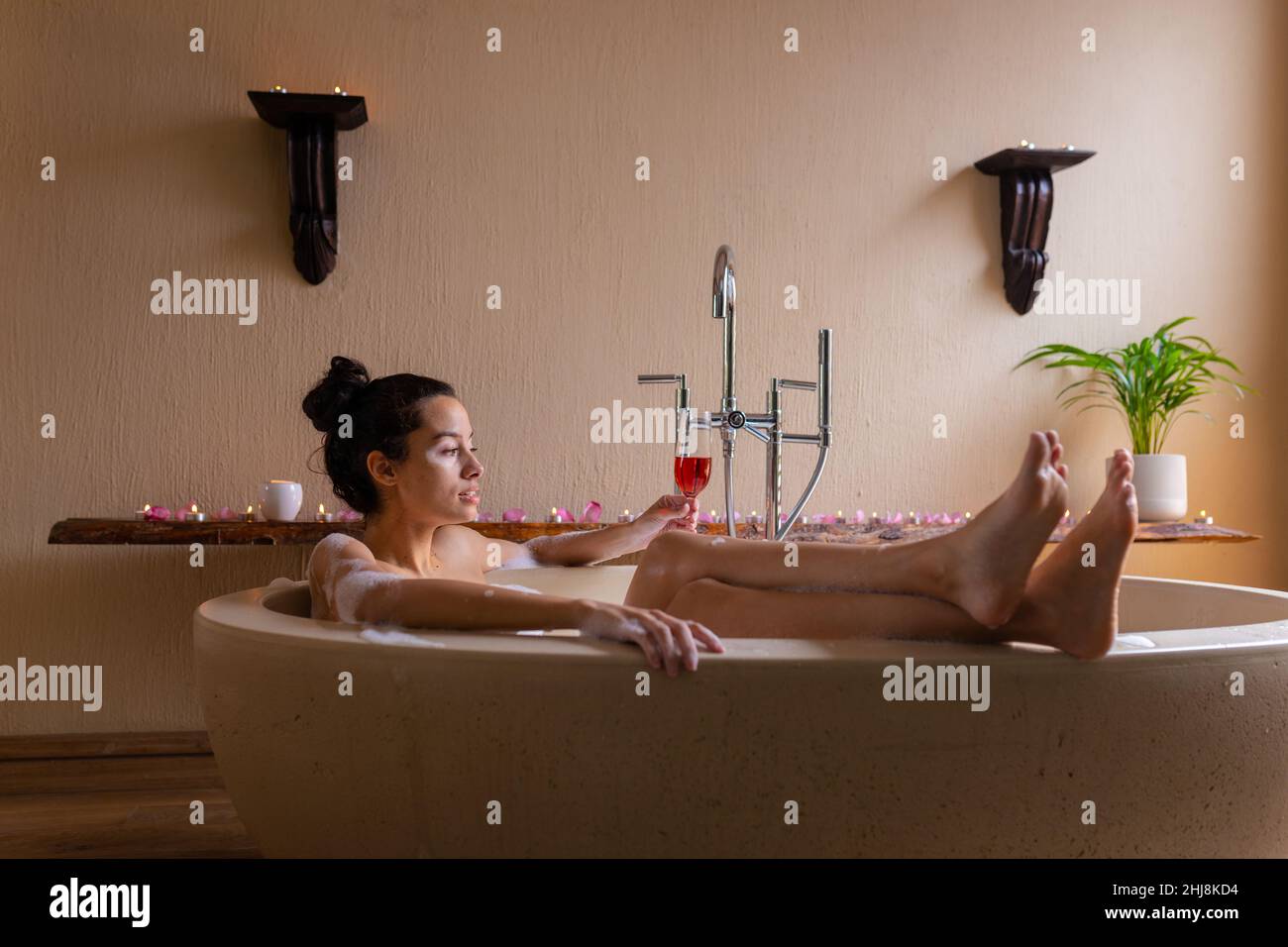 Jeune femme biraciale pensive ayant du vin rouge dans la baignoire au spa. Non modifié, spa, soins du corps, sensualité, style de vie,vitiligo et bien-être. Banque D'Images