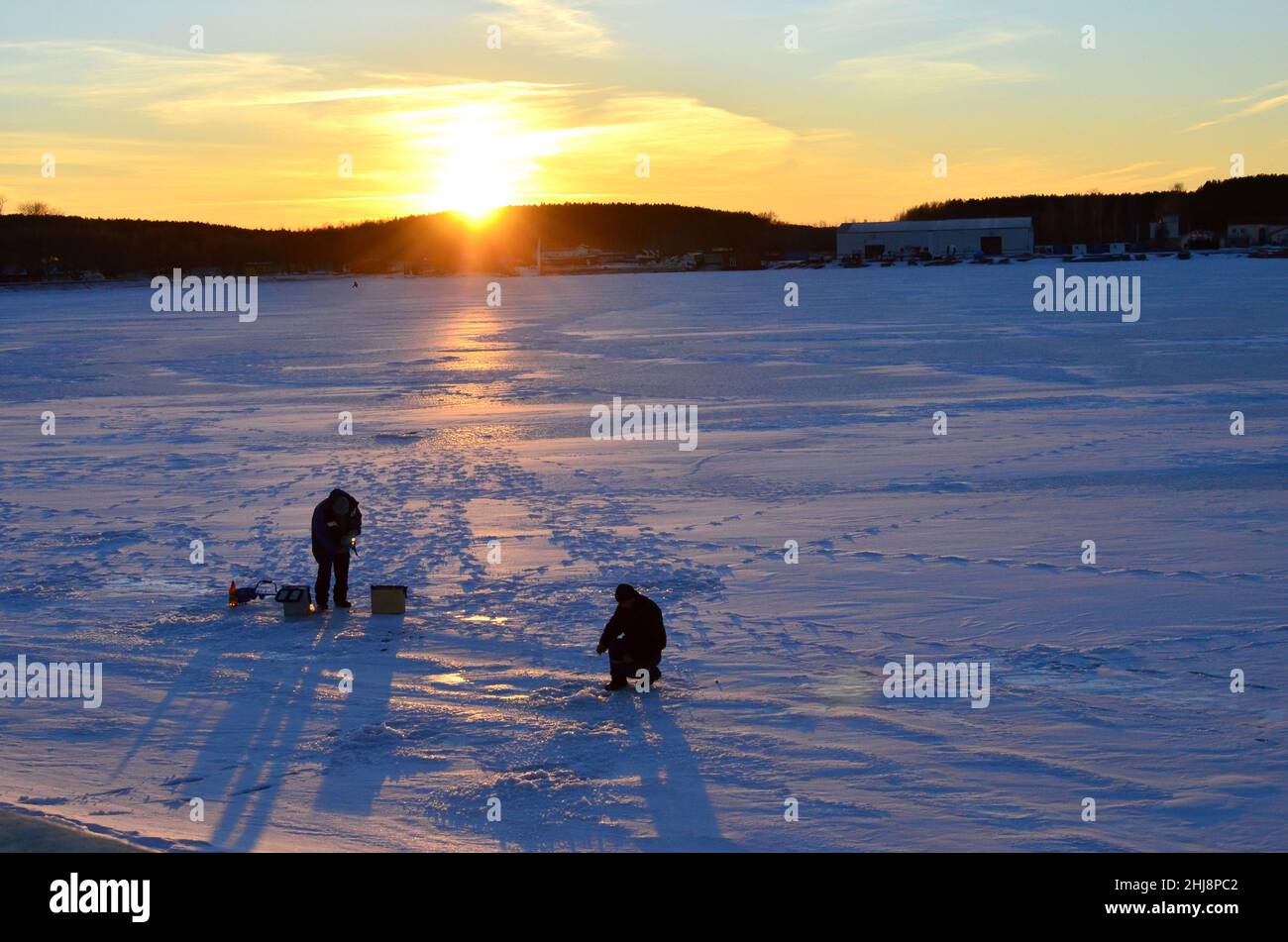 deux-pecheurs-sur-un-lac-gele-pechent-du-poisson-dans-un-trou-de-glace-sur-fond-de-coucher-de-soleil-l-hiver-arrive-les-plans-d-eau-gelent-ce-qui-rend-le-2hj8pc2.jpg