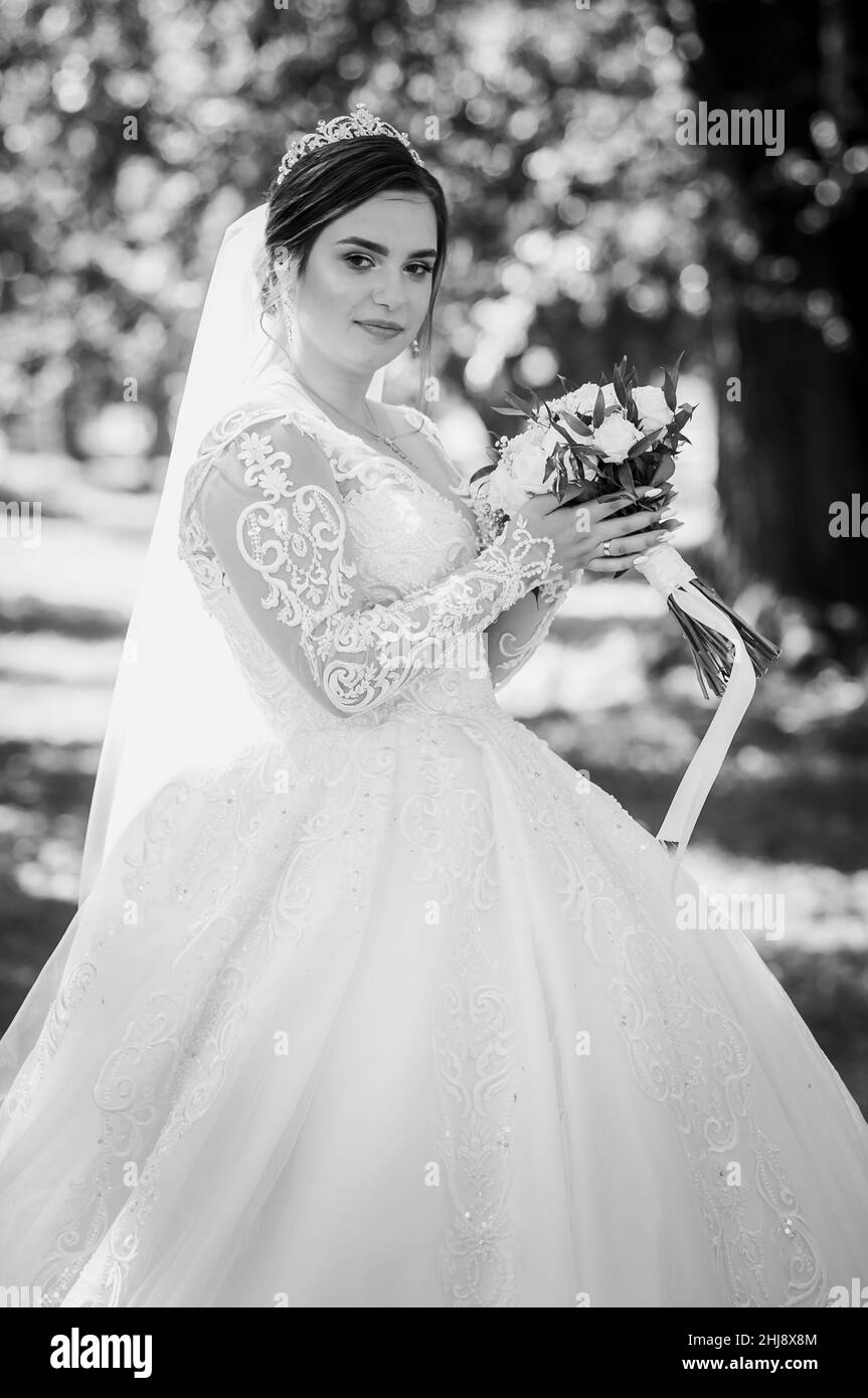 Portrait d'une mariée dans une belle robe blanche sur un fond vert.Mariée avec un bouquet de fleurs Banque D'Images