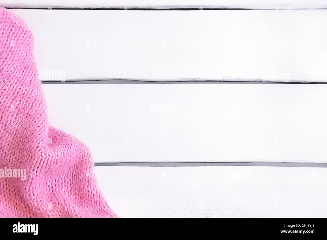 Tissu tricoté rose chaud sur table en bois blanc avec espace pour copier.Flat lay, vue de dessus Banque D'Images