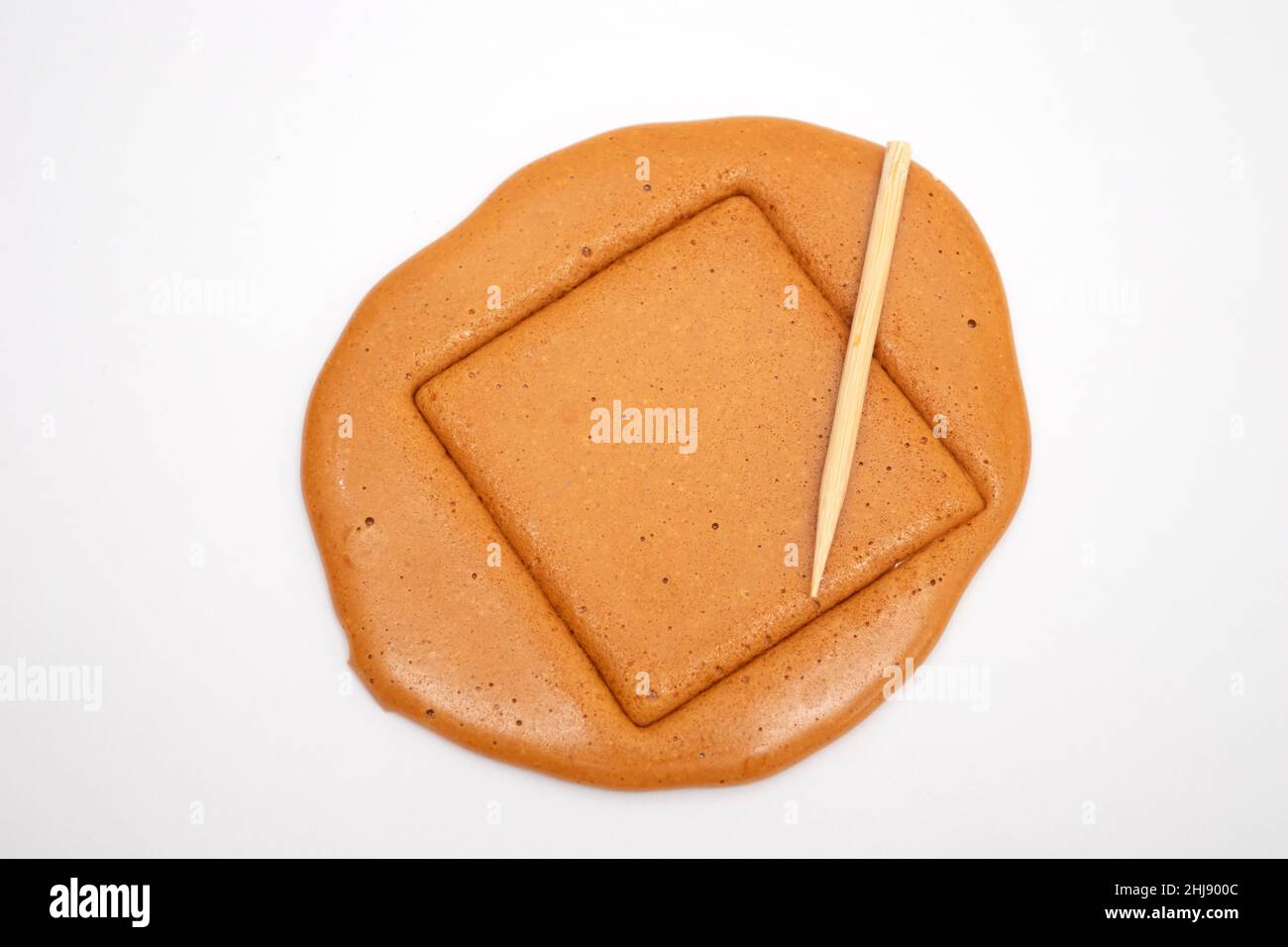 Biscuit coréen de sucre Dalgona avec une aiguille en métal. Banque D'Images