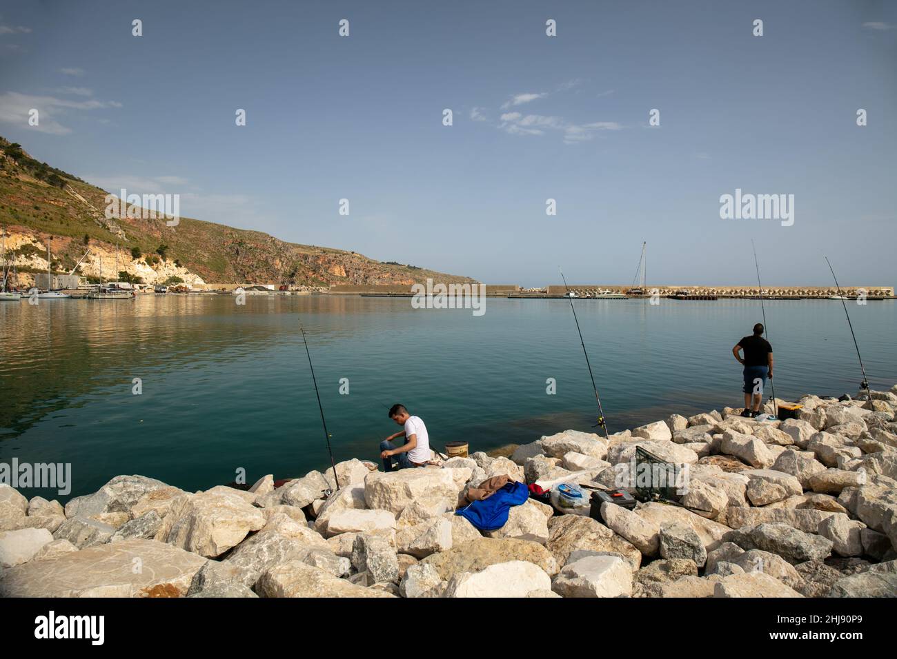 Castellammare del Golfo, province de Trapani, Sicile, Italie - Mai 5 2021: Vue panoramique de la marina avec deux pêcheurs avec des cannes à pêche Banque D'Images