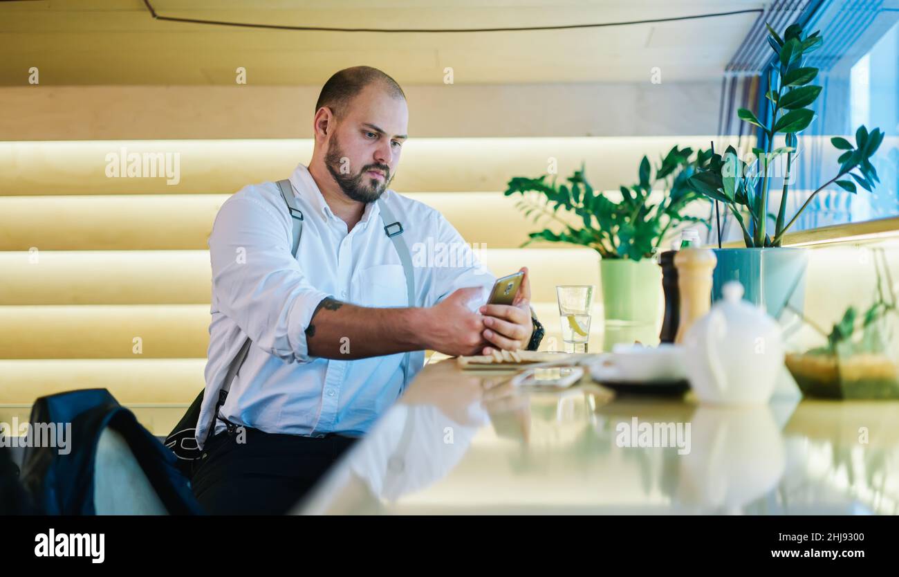 Homme attentionné utilisant un téléphone intelligent dans le restaurant Banque D'Images