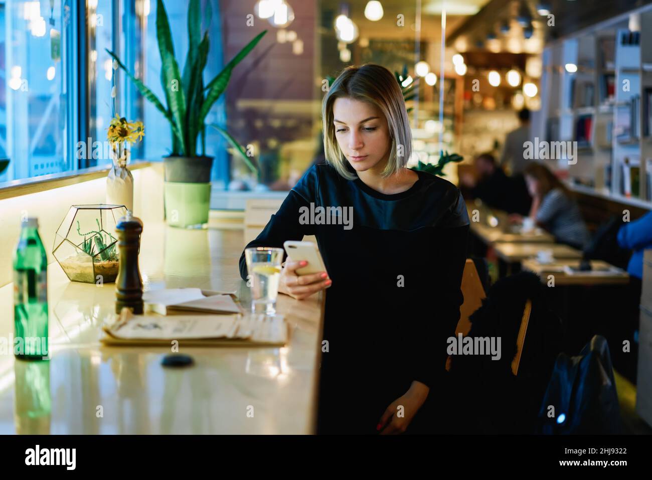 Femme assise dans un café avec un smartphone Banque D'Images