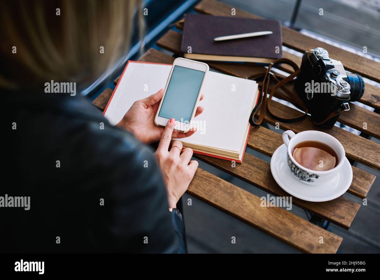 Une femme anonyme dans un café utilisant un smartphone Banque D'Images