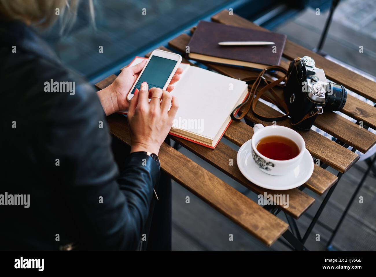 Une dame anonyme utilisant un smartphone dans un café Banque D'Images