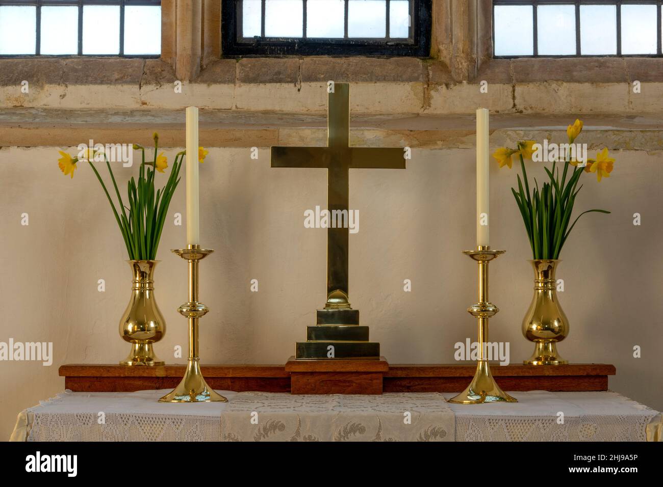 La table de l'autel de l'église du Prieuré de Sainte Marie, Letheringham, Suffolk avec une croix unie, deux chandeliers et vases en laiton de jonquilles Banque D'Images
