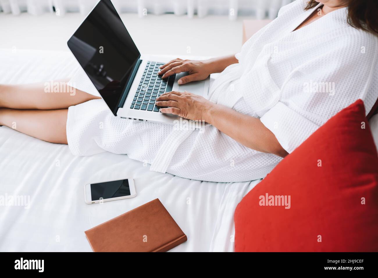 Crop femme tapant sur ordinateur portable refroidissant sur le lit Banque D'Images
