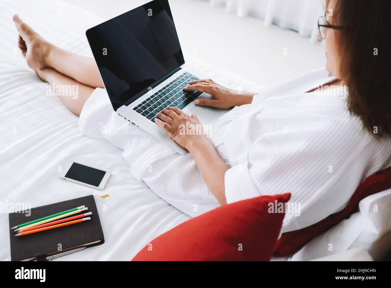 Femme méconnaissable avec un ordinateur portable sur le lit Banque D'Images