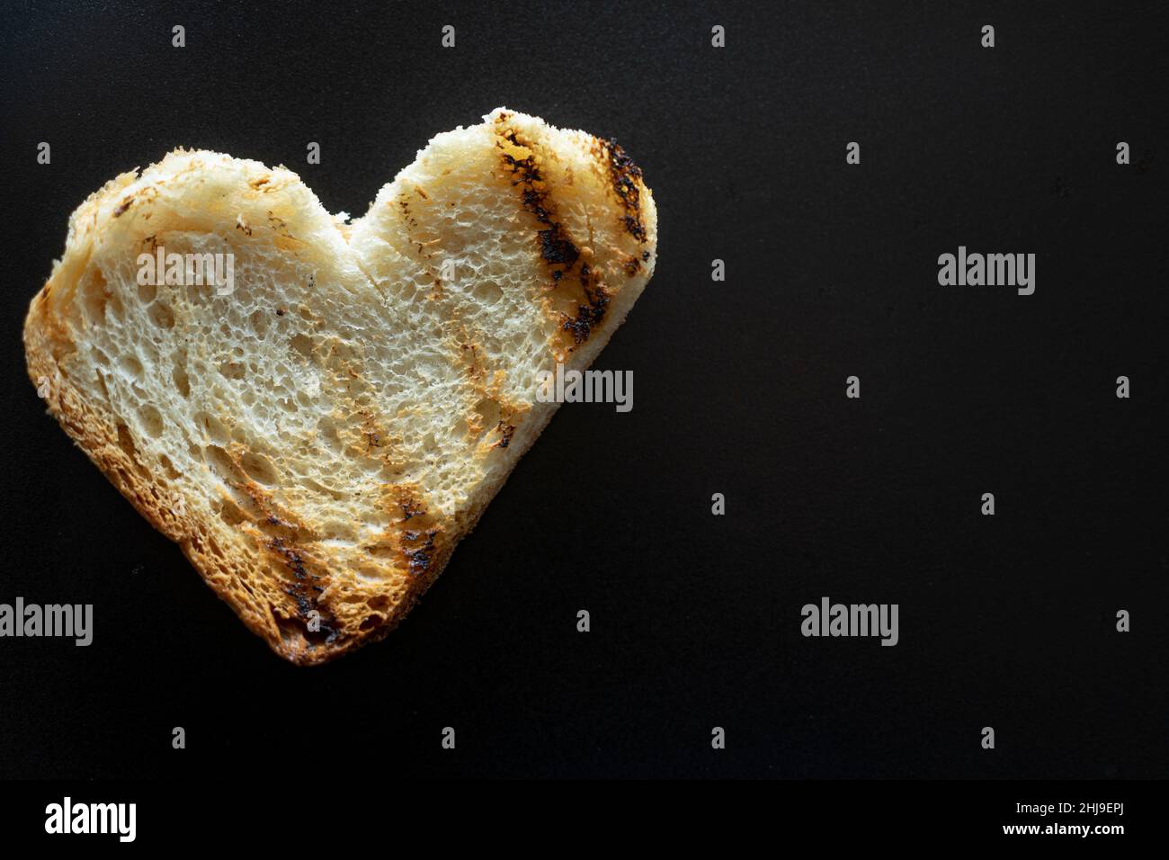 tranche de pain grillé en forme de cœur, macro de pain grillé isolé sur le noir, avec beaucoup d'espace de copie.Concept de l'amour de la nourriture Banque D'Images